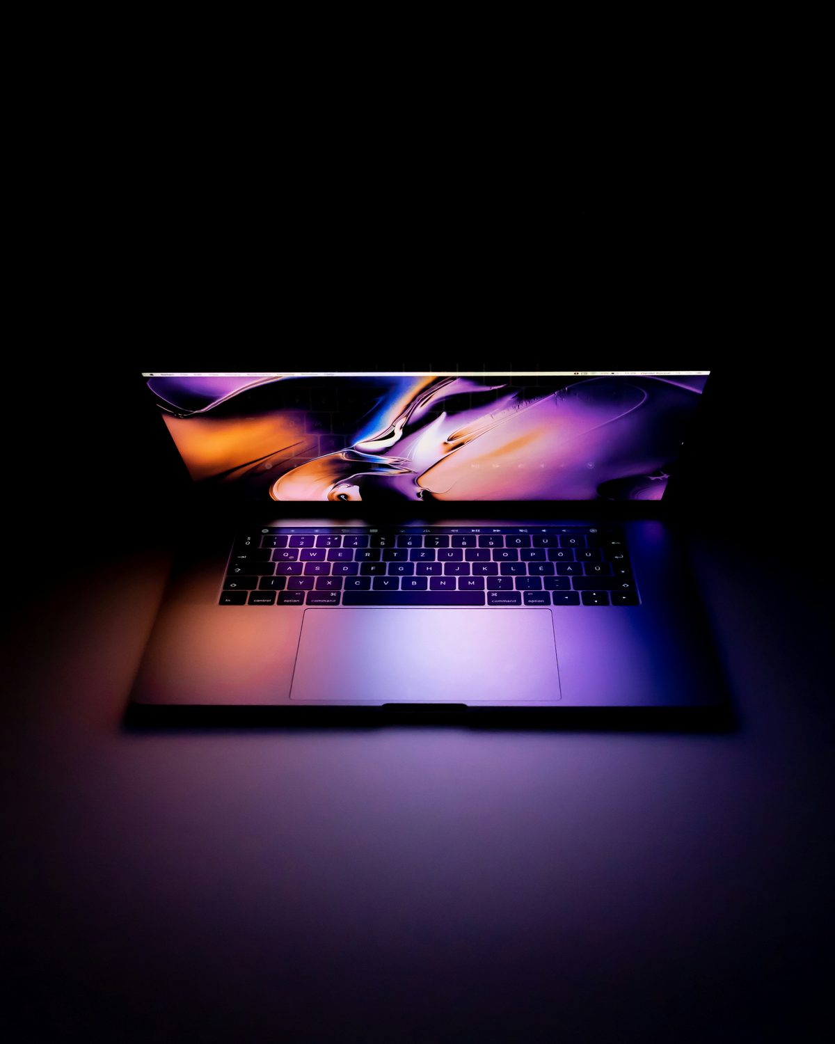An open laptop glowing in a darkened room, its screen the only source of light